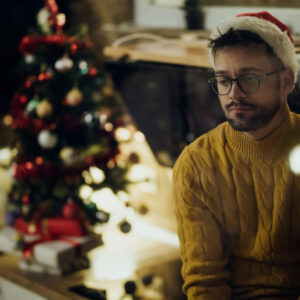 Young sad man spending Christmas Eve alone at home.