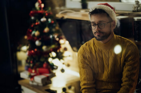 Young sad man spending Christmas Eve alone at home.